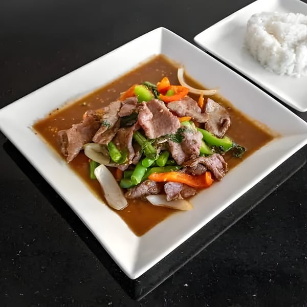 Thai beef stir-fry with green beans, bell peppers, and onions, served with white rice.