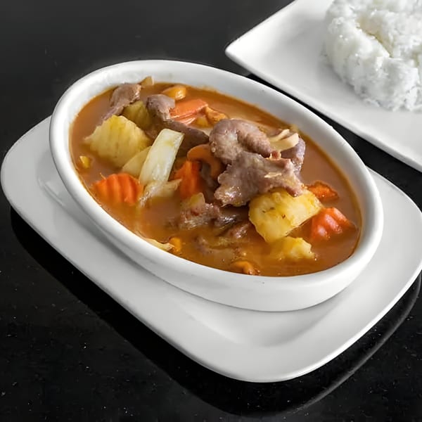 Thai Massaman curry with beef, potatoes, carrots, and pineapple, served with a side of white rice.