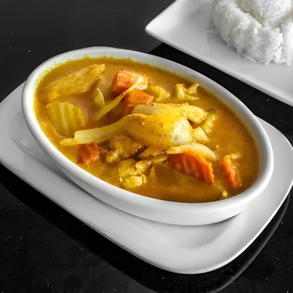 A bowl of yellow Thai curry with chicken, carrots, and cabbage, served with white rice.